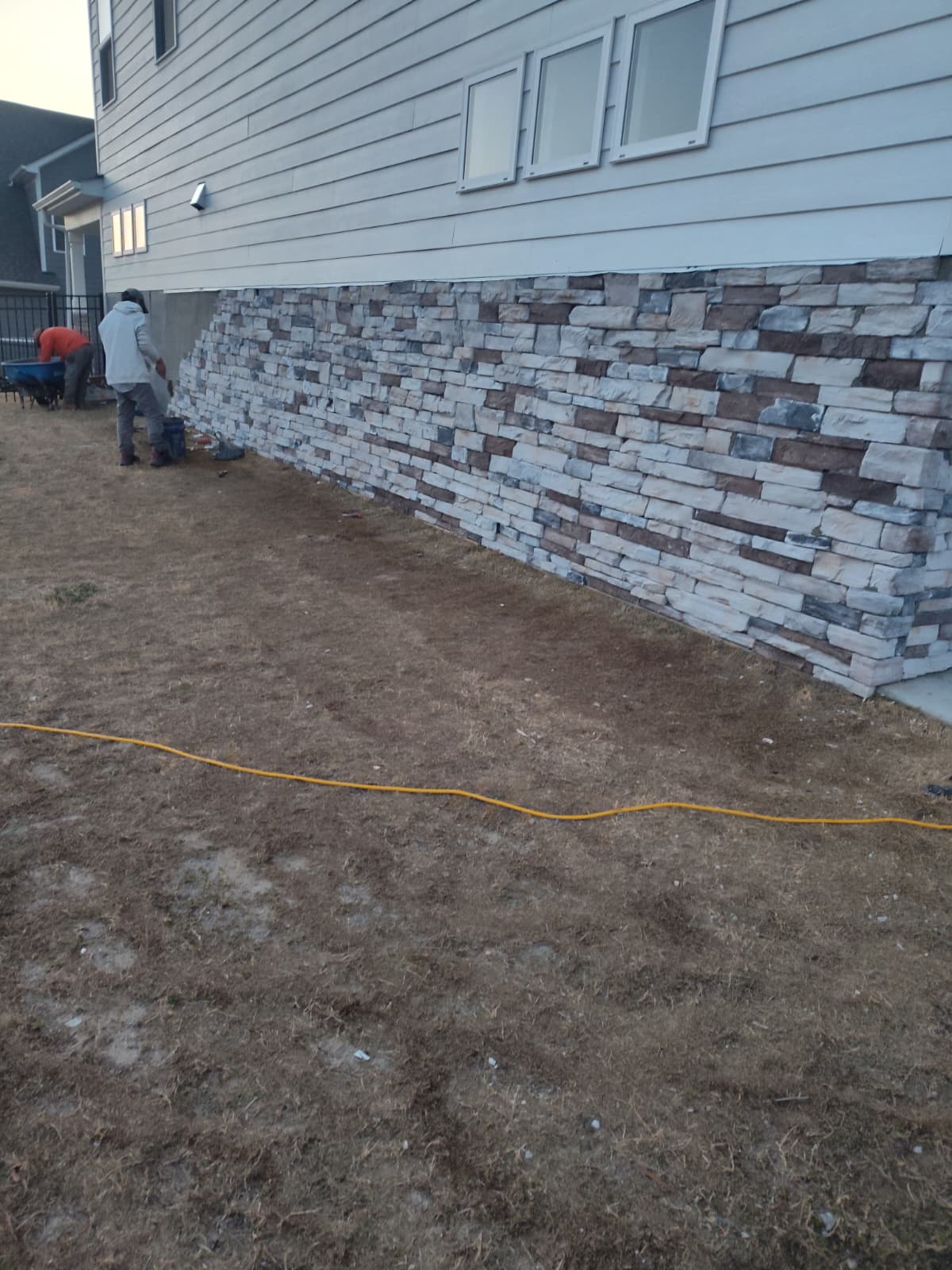 Completed stone veneer cladding on the exterior foundation wall of a home